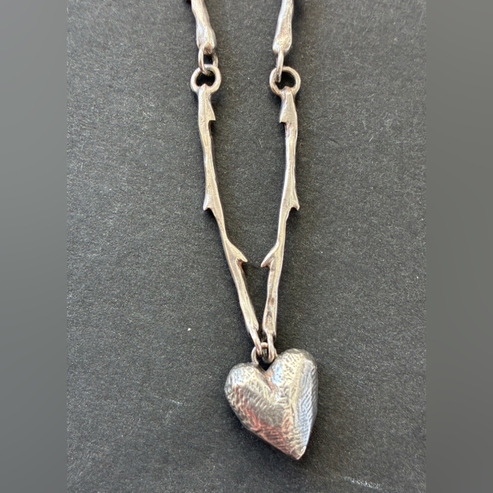 A silver necklace of thorns with a hammered heart, artisan made